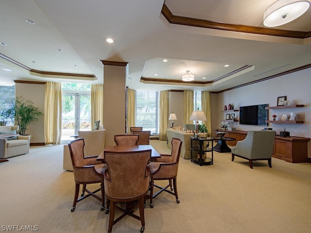 carpeted dining room featuring a raised ceiling and crown molding