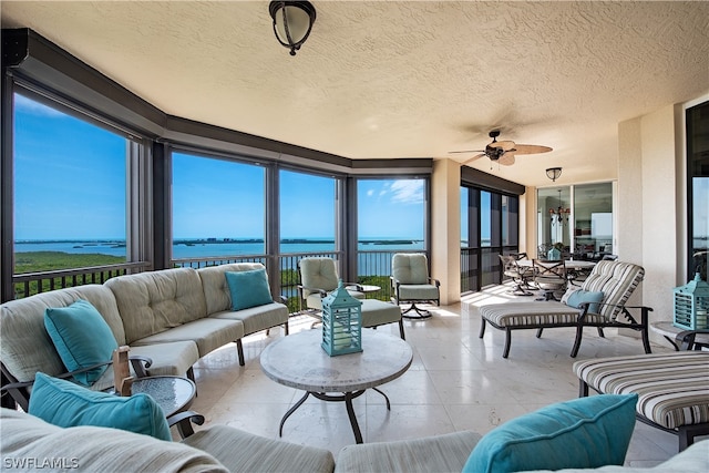 sunroom / solarium with ceiling fan and a water view