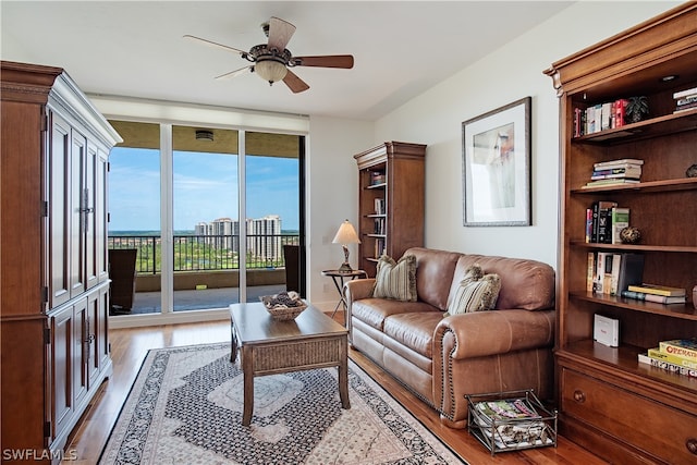 living room with expansive windows, light hardwood / wood-style flooring, and ceiling fan