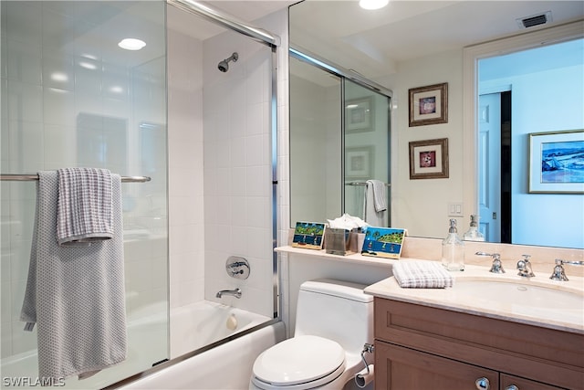 full bathroom with vanity, bath / shower combo with glass door, and toilet