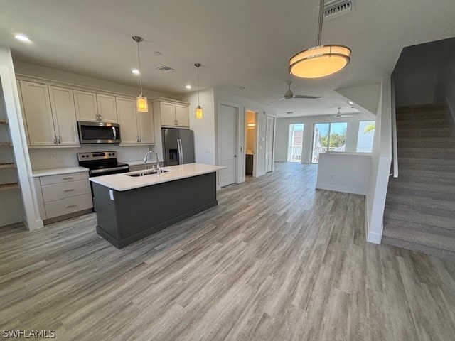 kitchen with appliances with stainless steel finishes, ceiling fan, sink, and light hardwood / wood-style floors