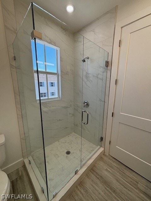 bathroom featuring hardwood / wood-style floors, walk in shower, and toilet