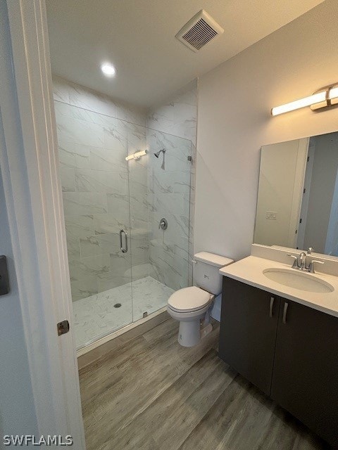 full bathroom with a marble finish shower, visible vents, toilet, wood finished floors, and vanity