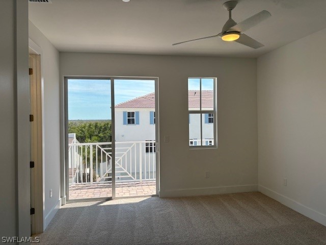 carpeted empty room featuring ceiling fan and baseboards