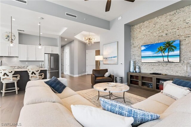 living room featuring ceiling fan with notable chandelier and hardwood / wood-style flooring