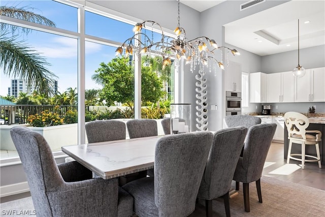 dining room with visible vents, a notable chandelier, and wood finished floors