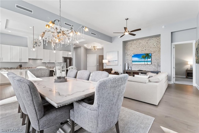 dining space featuring ceiling fan with notable chandelier and light hardwood / wood-style floors