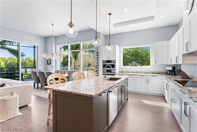 kitchen with sink, white cabinetry, and an island with sink