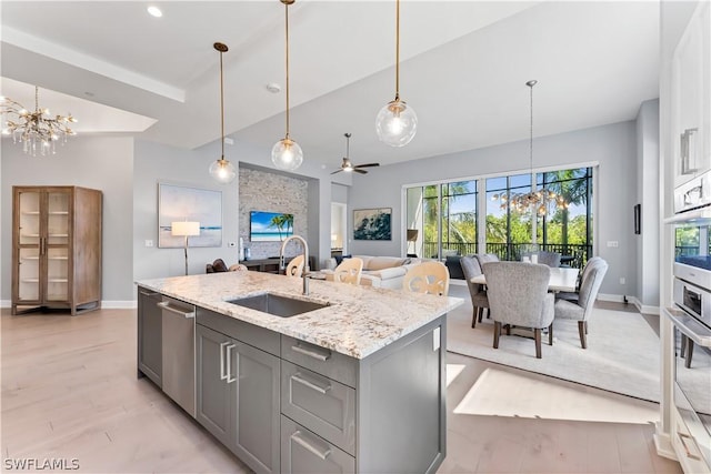 kitchen featuring ceiling fan with notable chandelier, stainless steel appliances, sink, gray cabinets, and hanging light fixtures