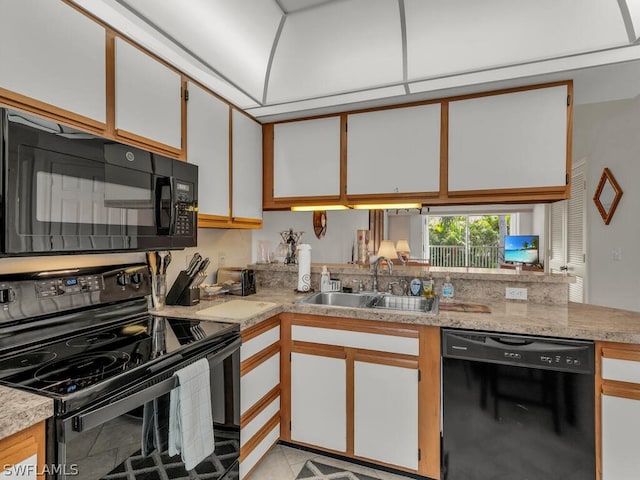 kitchen with light stone counters, light tile floors, sink, black appliances, and white cabinets