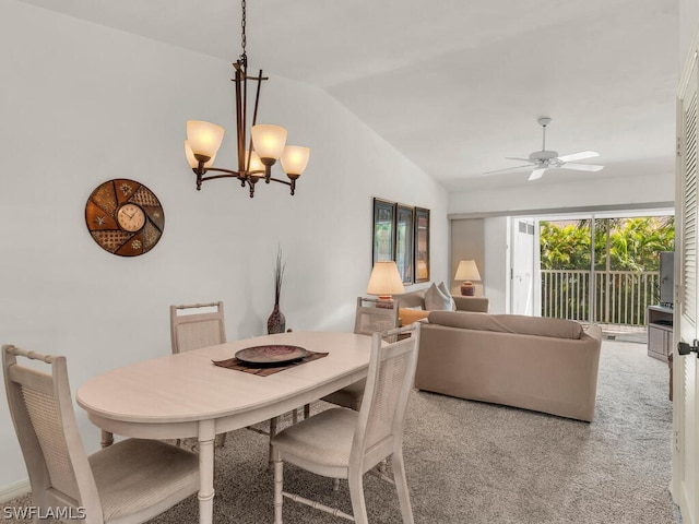 carpeted dining space featuring ceiling fan with notable chandelier and lofted ceiling