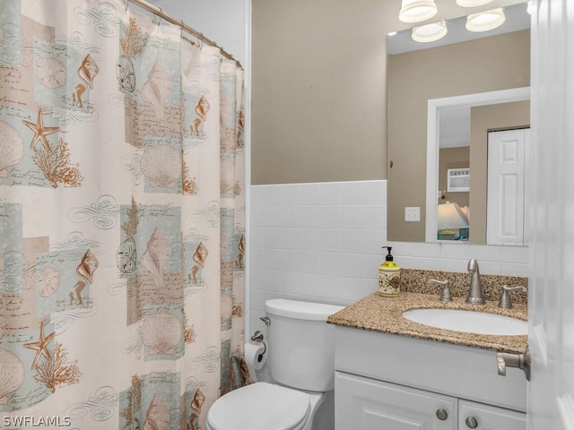 bathroom featuring vanity, tile walls, and toilet