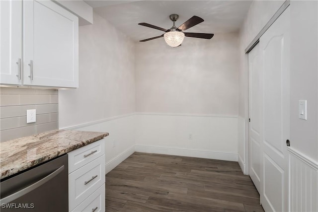 kitchen with stainless steel dishwasher, dark hardwood / wood-style flooring, light stone counters, and white cabinets