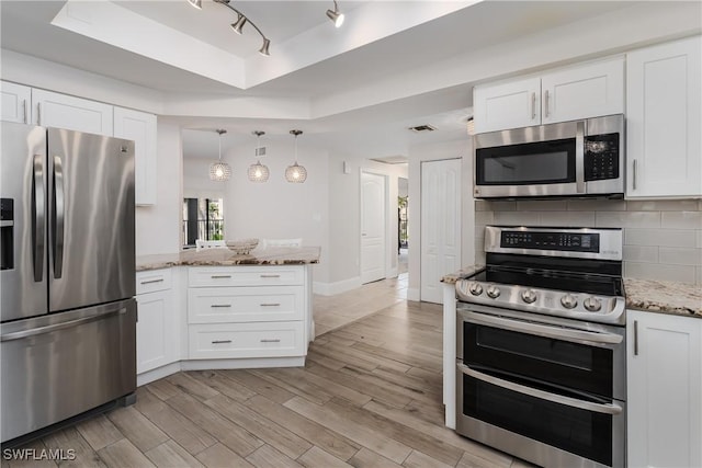 kitchen with appliances with stainless steel finishes, tasteful backsplash, light stone counters, white cabinets, and a tray ceiling