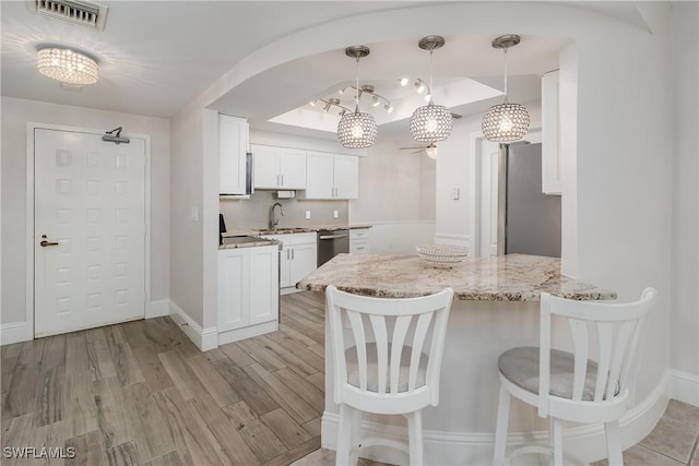 kitchen featuring appliances with stainless steel finishes, white cabinetry, hanging light fixtures, and kitchen peninsula