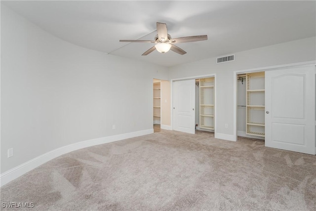 unfurnished bedroom with ceiling fan, two closets, and carpet floors