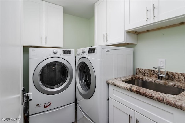 clothes washing area featuring sink, separate washer and dryer, and cabinets