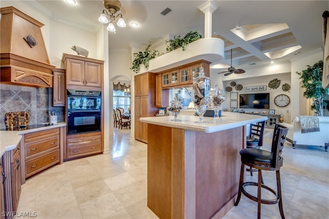 kitchen featuring coffered ceiling, custom exhaust hood, tasteful backsplash, a kitchen bar, and ceiling fan