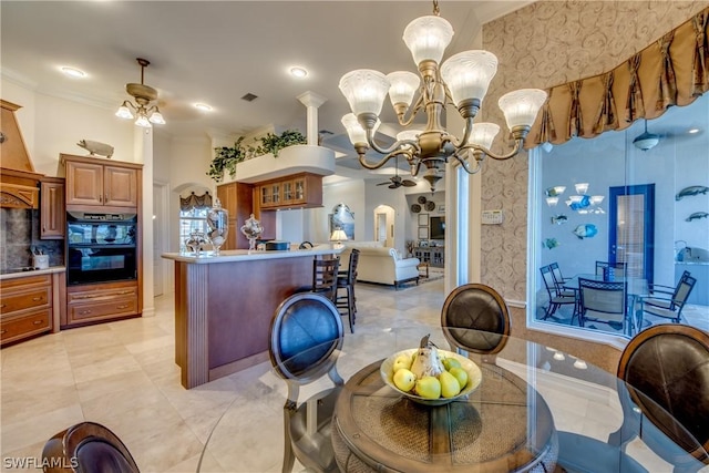 dining area featuring arched walkways, visible vents, wallpapered walls, ornamental molding, and ceiling fan with notable chandelier