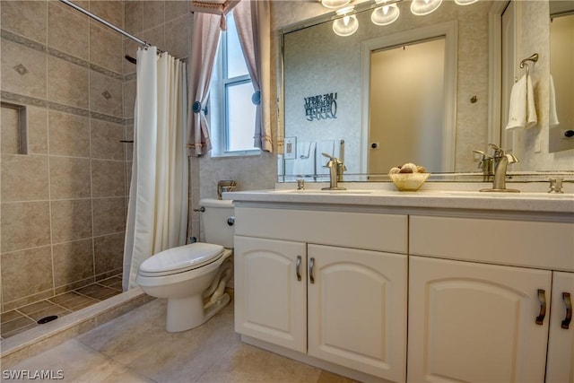 full bath featuring toilet, double vanity, a tile shower, and a sink