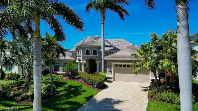 view of front of property with an attached garage, a front yard, decorative driveway, and stucco siding