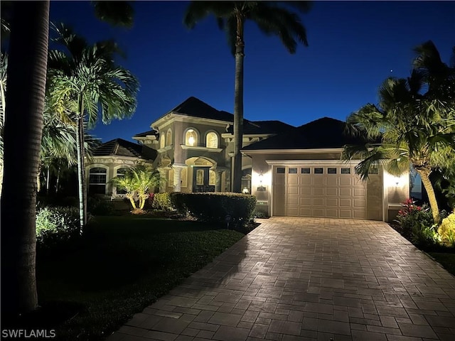 mediterranean / spanish house with decorative driveway, an attached garage, and stucco siding