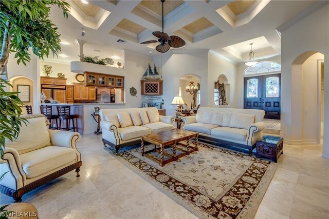 living room featuring coffered ceiling, ceiling fan with notable chandelier, light tile patterned floors, and a towering ceiling