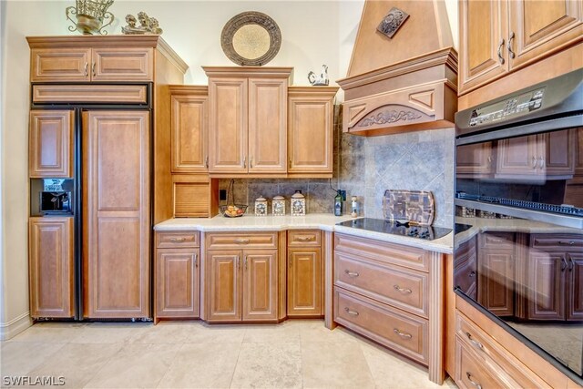 kitchen featuring paneled refrigerator, black electric stovetop, light tile patterned flooring, and decorative backsplash