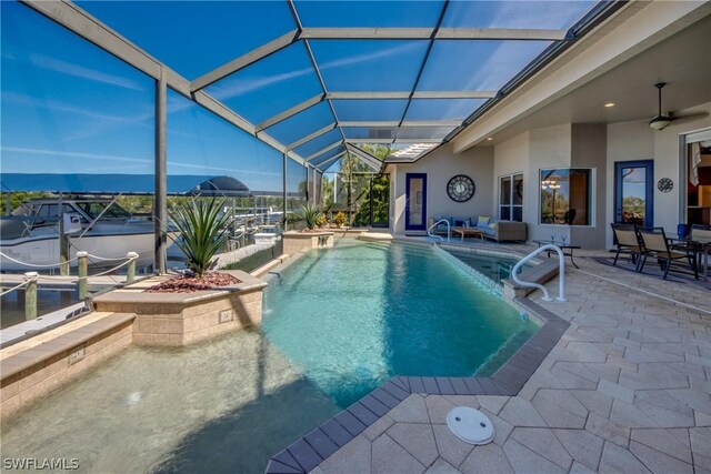 view of swimming pool with ceiling fan, a patio, and glass enclosure