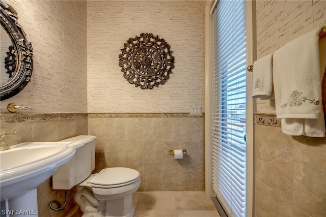 half bath featuring tile walls, a sink, toilet, and tile patterned floors