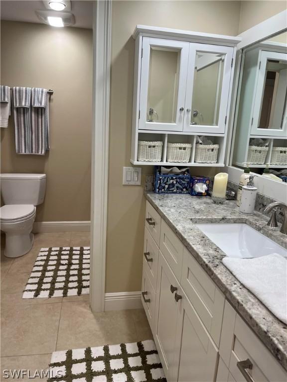 bathroom with tile patterned flooring, toilet, vanity, and baseboards