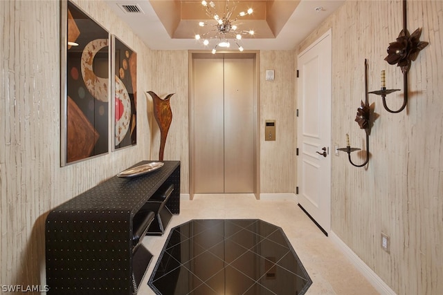 mudroom with a raised ceiling, elevator, and a chandelier