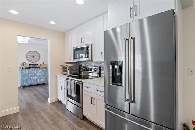 kitchen featuring stainless steel appliances, white cabinets, light wood-type flooring, and tasteful backsplash