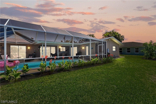 back house at dusk with a lanai and a yard