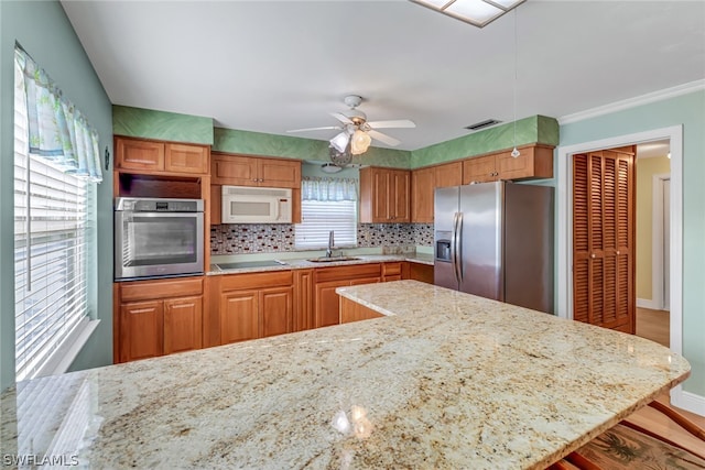 kitchen with light stone countertops, stainless steel appliances, tasteful backsplash, and ceiling fan