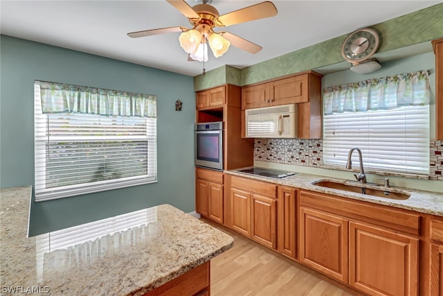 kitchen featuring sink, a healthy amount of sunlight, stainless steel oven, and light wood-type flooring