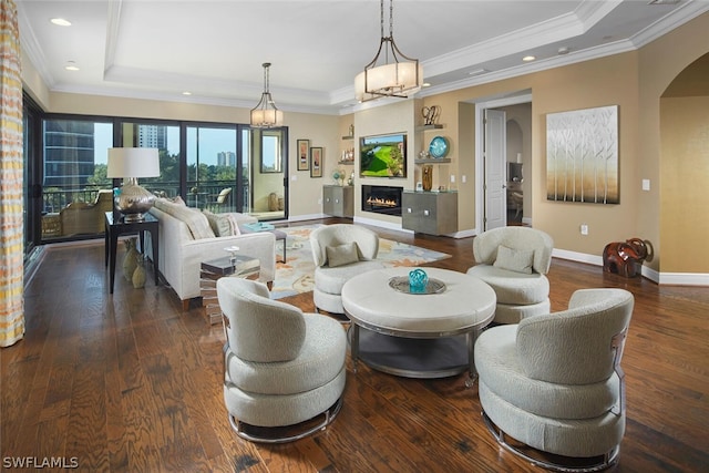 living room with an inviting chandelier, crown molding, dark wood-type flooring, and a raised ceiling