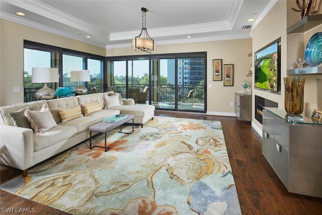 living room with a raised ceiling, dark hardwood / wood-style floors, ornamental molding, and a notable chandelier