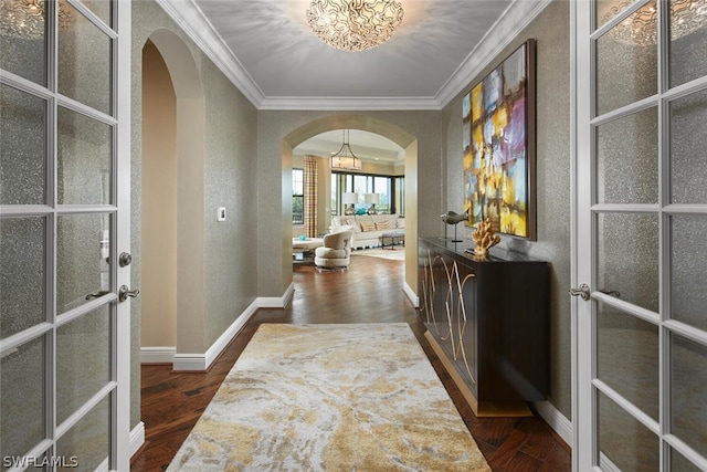 hall with a notable chandelier, ornamental molding, dark hardwood / wood-style floors, and french doors