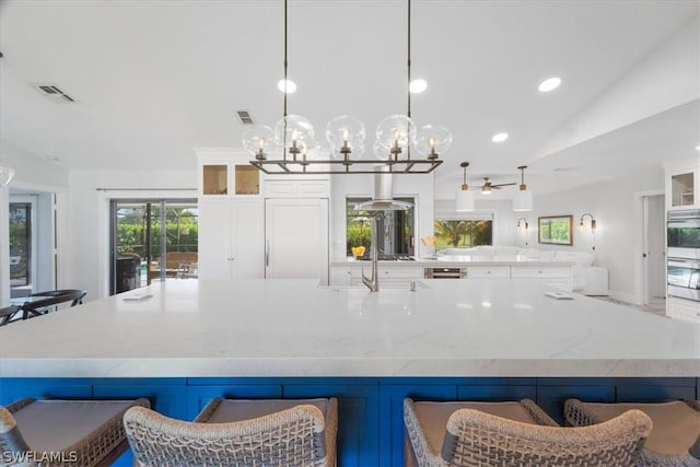 kitchen with pendant lighting, ceiling fan, lofted ceiling, and a breakfast bar