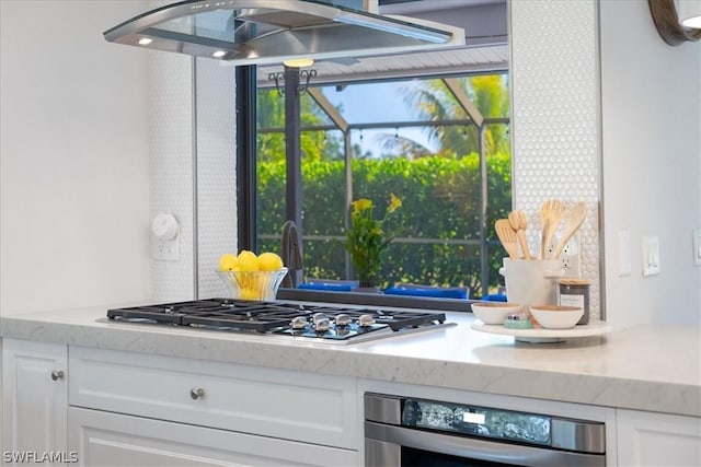 kitchen with white cabinetry, oven, light stone counters, and stainless steel gas cooktop