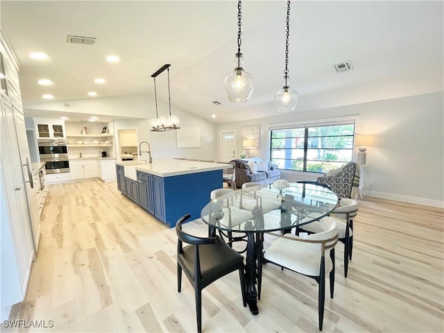 dining room with light hardwood / wood-style flooring, lofted ceiling, and sink