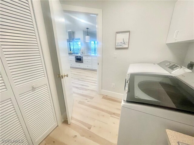 laundry area featuring light hardwood / wood-style floors, cabinets, and independent washer and dryer