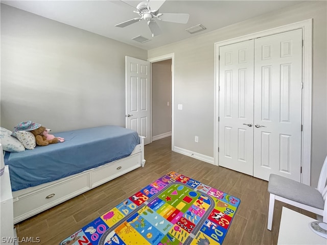 bedroom with dark wood-type flooring, ceiling fan, and a closet