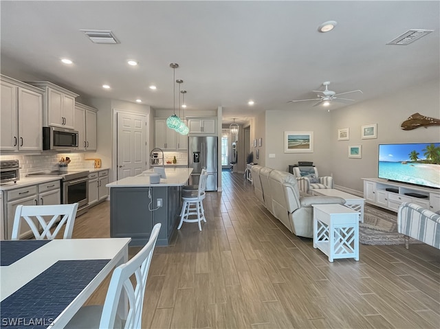 living room featuring sink, light hardwood / wood-style floors, and ceiling fan