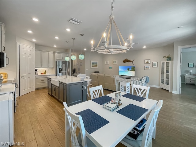 dining room featuring sink, a chandelier, and light hardwood / wood-style floors