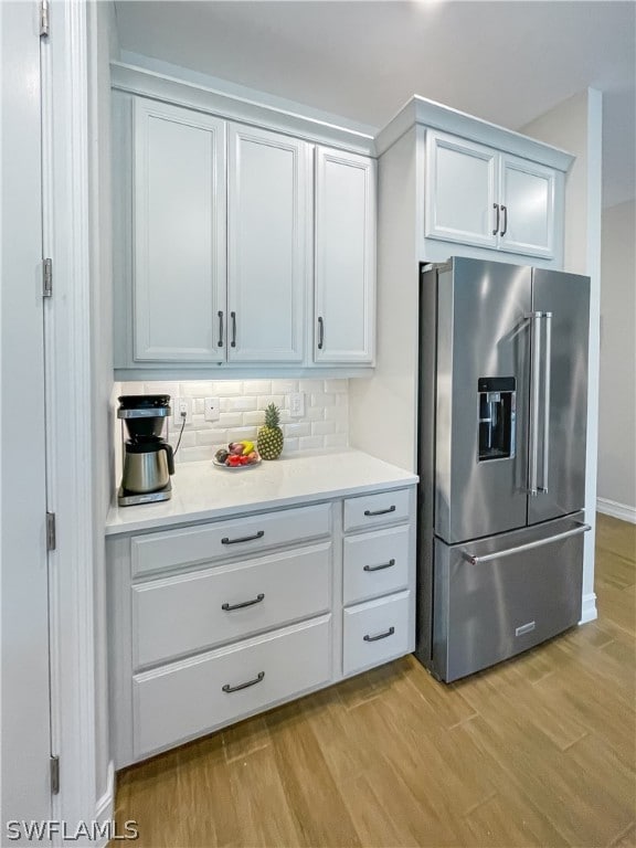 kitchen featuring high end fridge, white cabinets, light hardwood / wood-style floors, and decorative backsplash