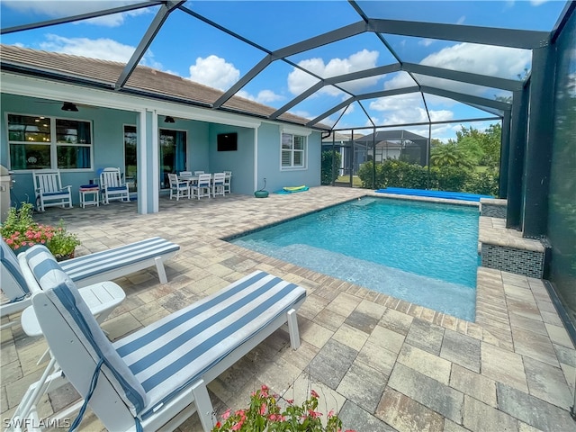 view of swimming pool featuring a patio, ceiling fan, and glass enclosure