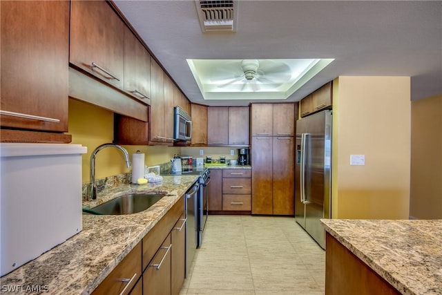 kitchen with light stone countertops, sink, ceiling fan, and stainless steel appliances