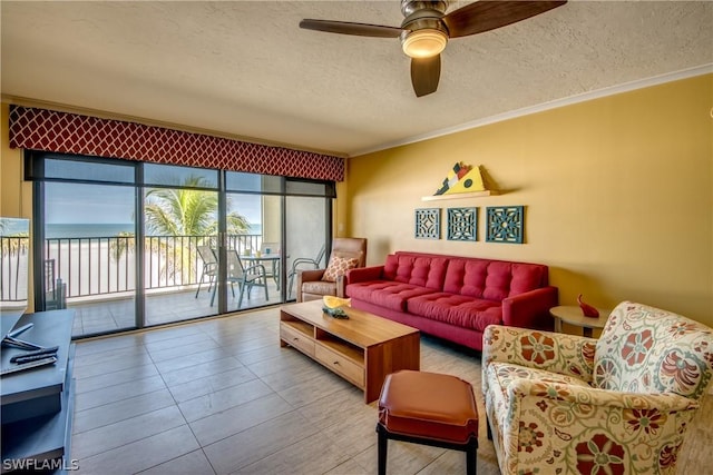 living room featuring ceiling fan, a water view, a textured ceiling, and ornamental molding